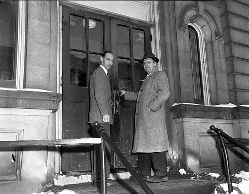Two men standing in front of a doorway.