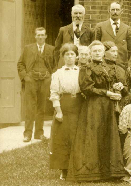 Man standing behind group.