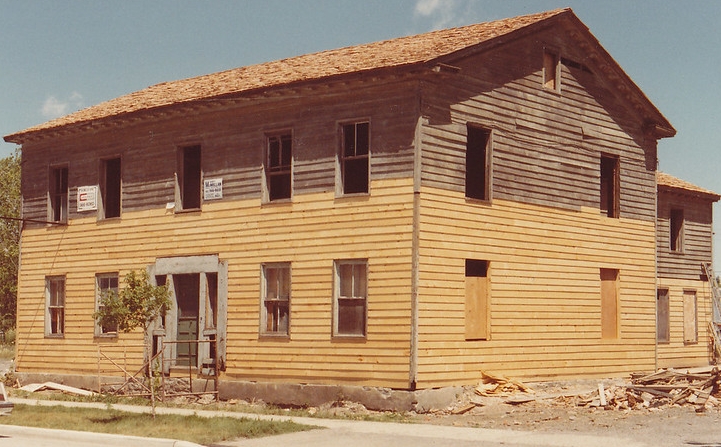 House undergoing restoration of wooden siding and shingle roof.