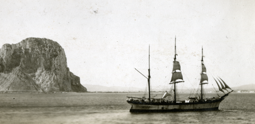 Sailing ship by a cliff.