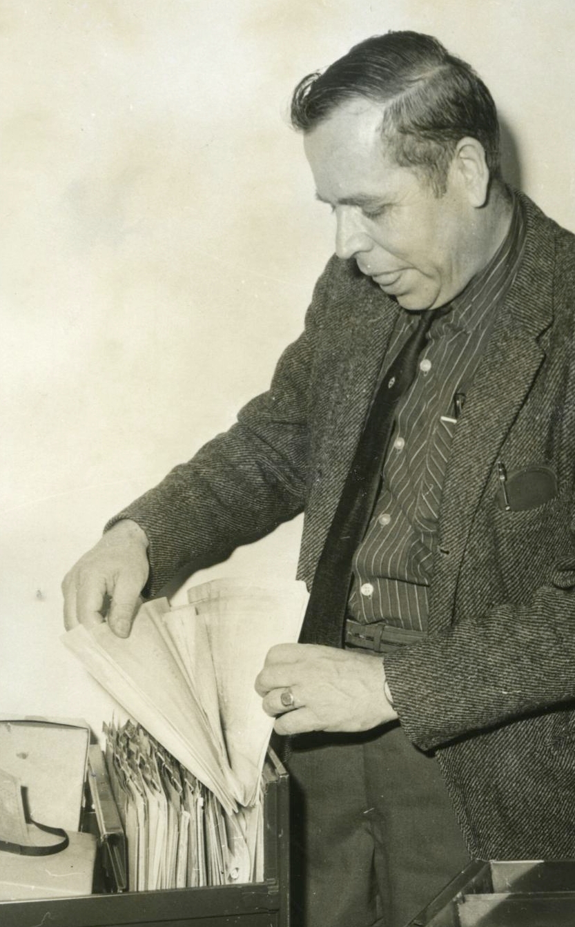 Man looking through file in a filing cabinet.